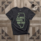 Illinois Roots Run Deep tee in black with sage print, laid flat on weathered wood