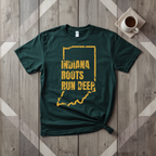 Indiana Roots Run Deep tee in forest green with mustard print, laid flat on weathered wood