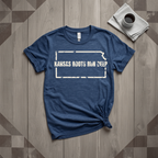 Kansas Roots Run Deep tee in heather navy with cream print, laid flat on weathered wood