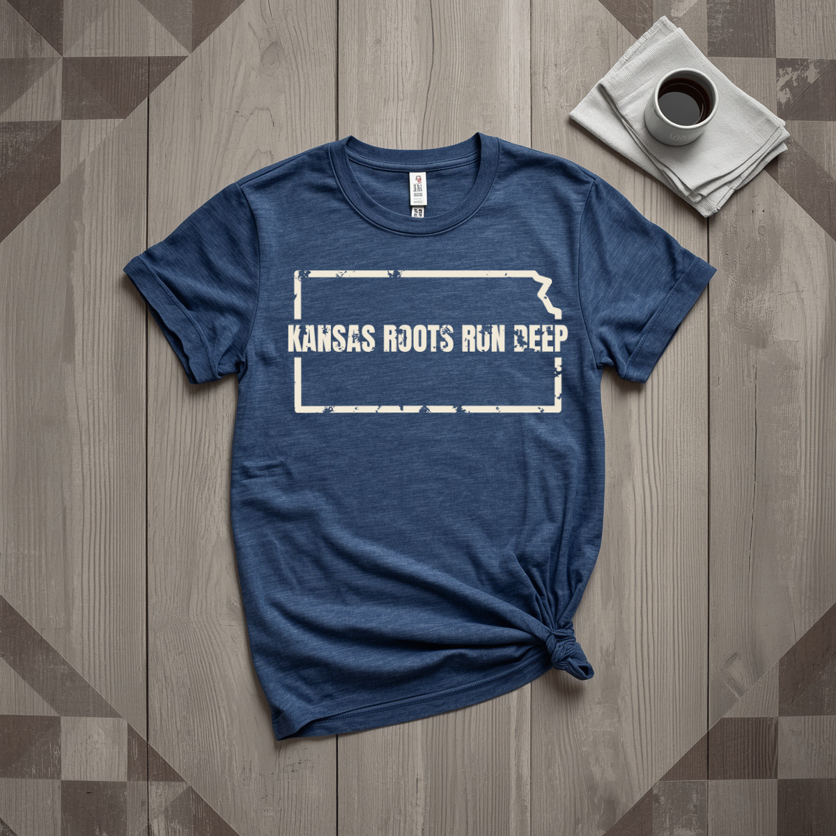 Kansas Roots Run Deep tee in heather navy with cream print, laid flat on weathered wood