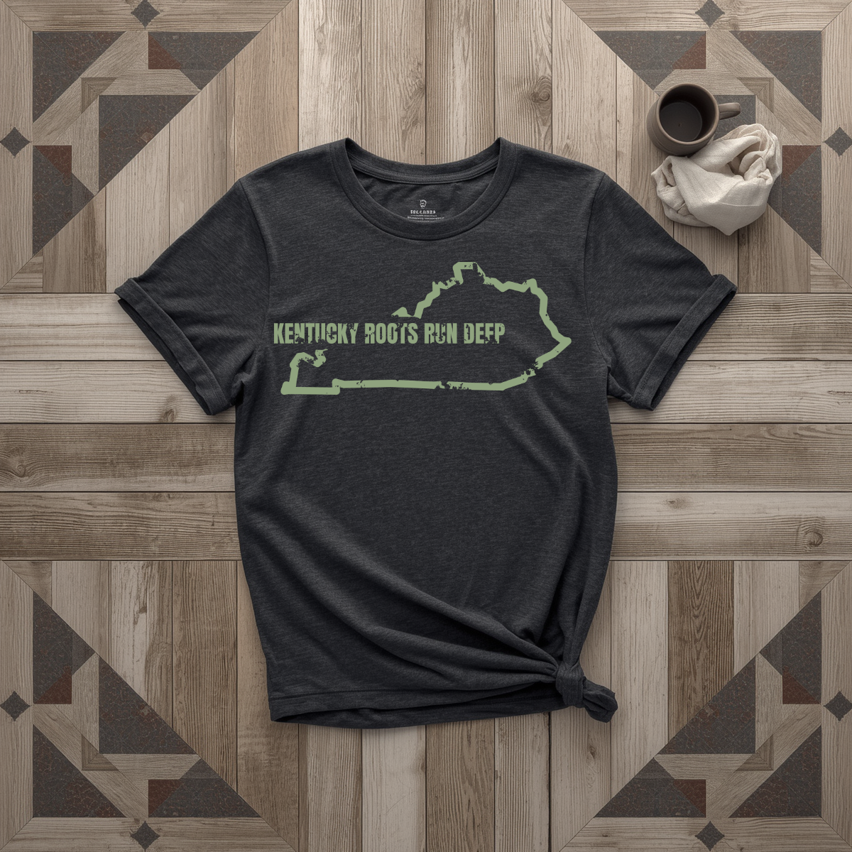 Kentucky Roots Run Deep tee in black with sage print, laid flat on weathered wood