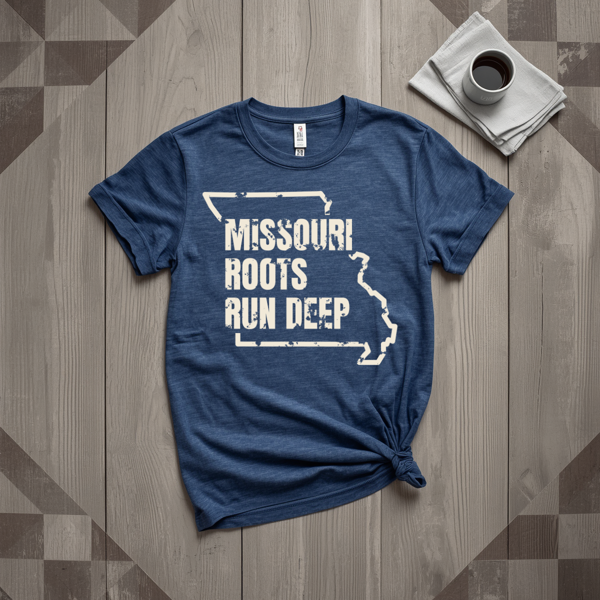 Missouri Roots Run Deep tee in heather navy with cream print, laid flat on weathered wood