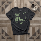 Ohio Roots Run Deep tee in black with sage print, laid flat on weathered wood